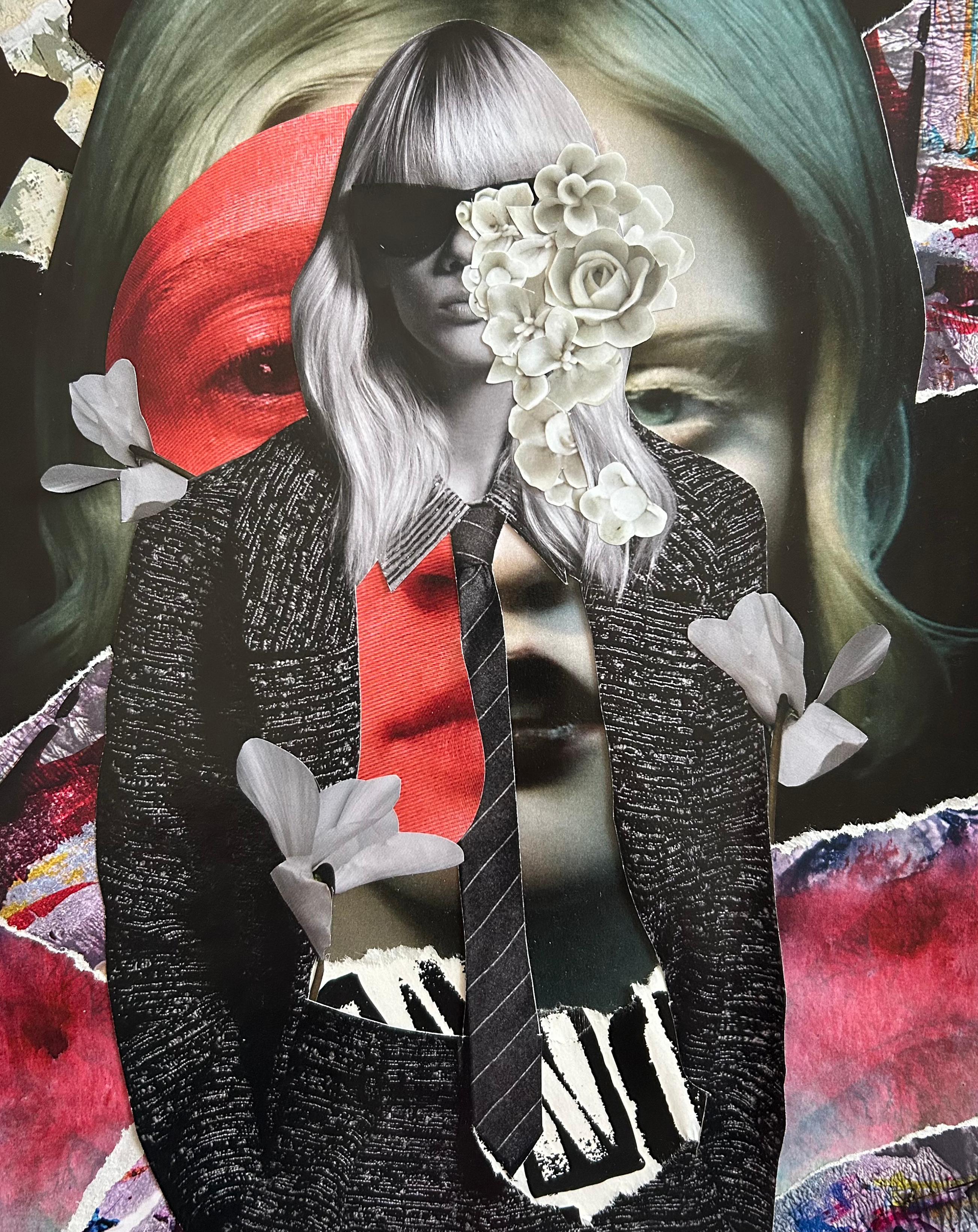 Hidden Expression: figure in a black jacket and red tie whose face is hidden behind grey-green hair, white flowers and a black mask